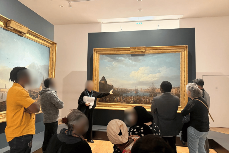 Bénéficiaires de Défi Services + observant un tableau au Musée national de la Marine, guidés par Clémentine lors de la visite « Le goût de la mer »